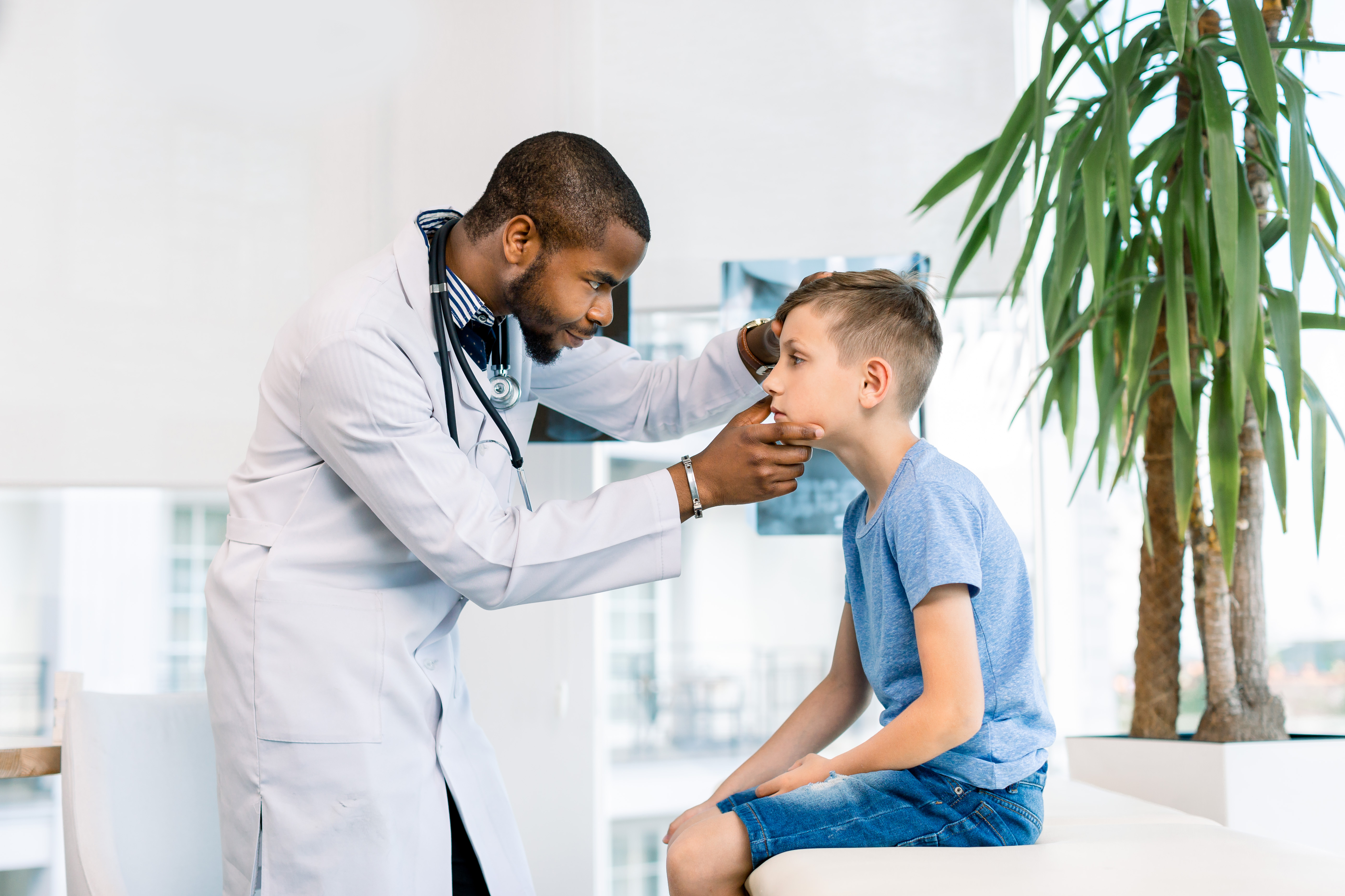 Handsome African male Doctor Examining Eyes of a little boy in medical clinic